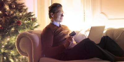 Man shopping online next to Christmas tree